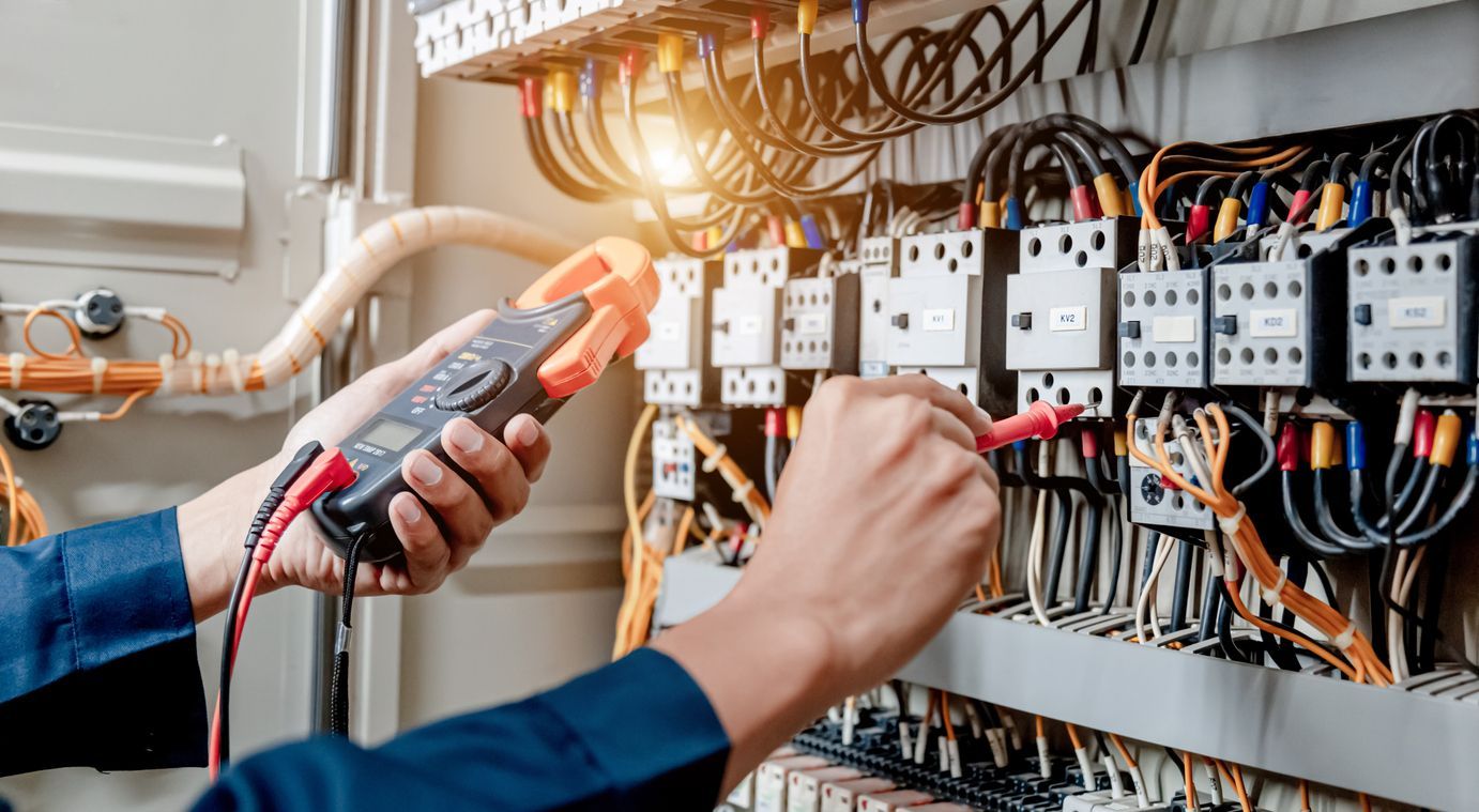 Anderson Electric electrician testing electrical panel with a multimeter, wires visible, indoor sett