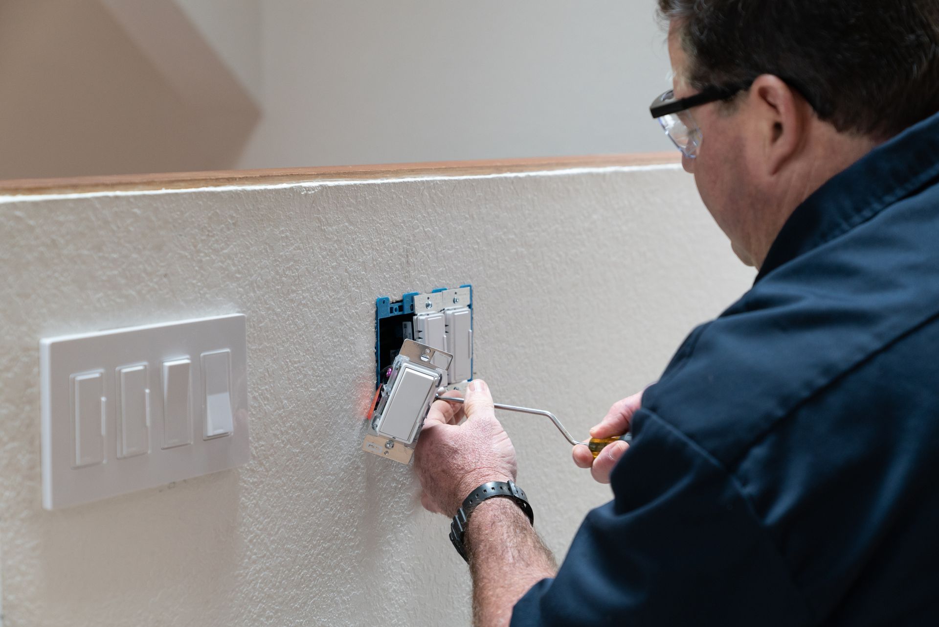 Electrician working in home installing dimmer switched in wall.