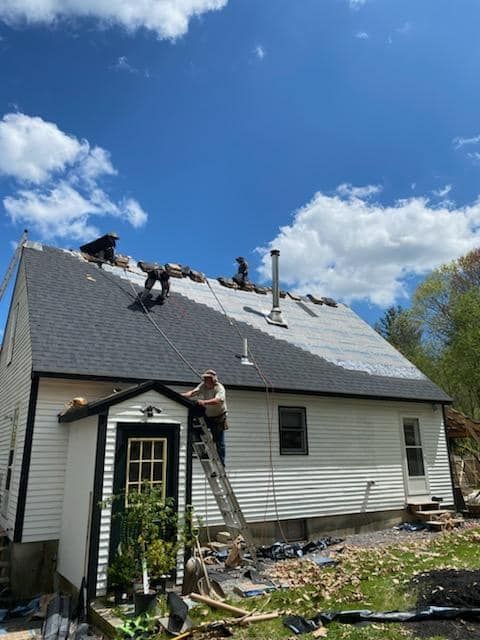 A man wearing a tool belt is working on a roof.