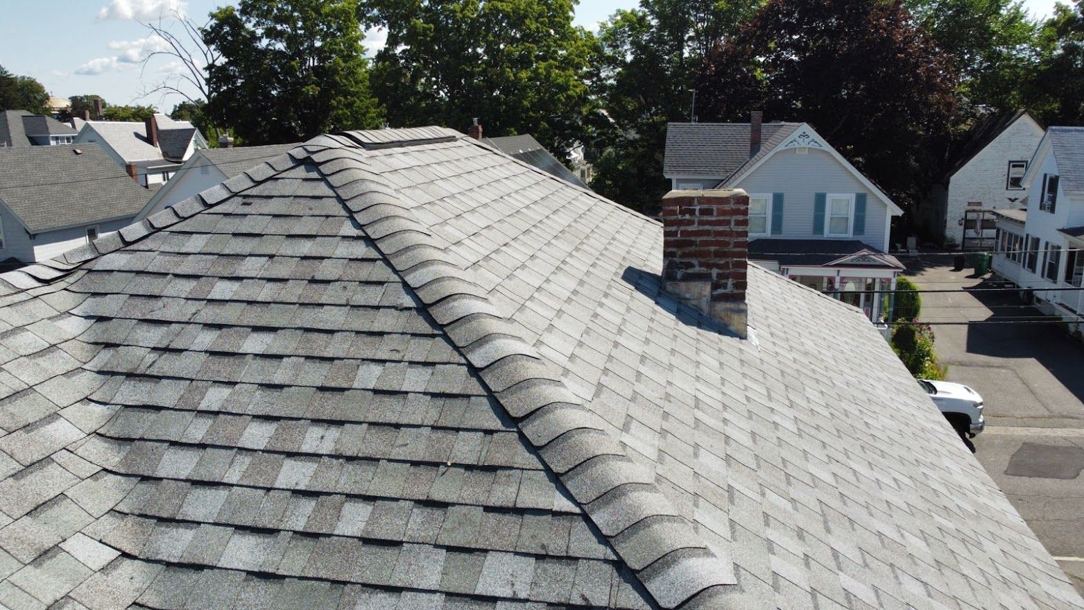 A close up of a black tile roof on a white background.