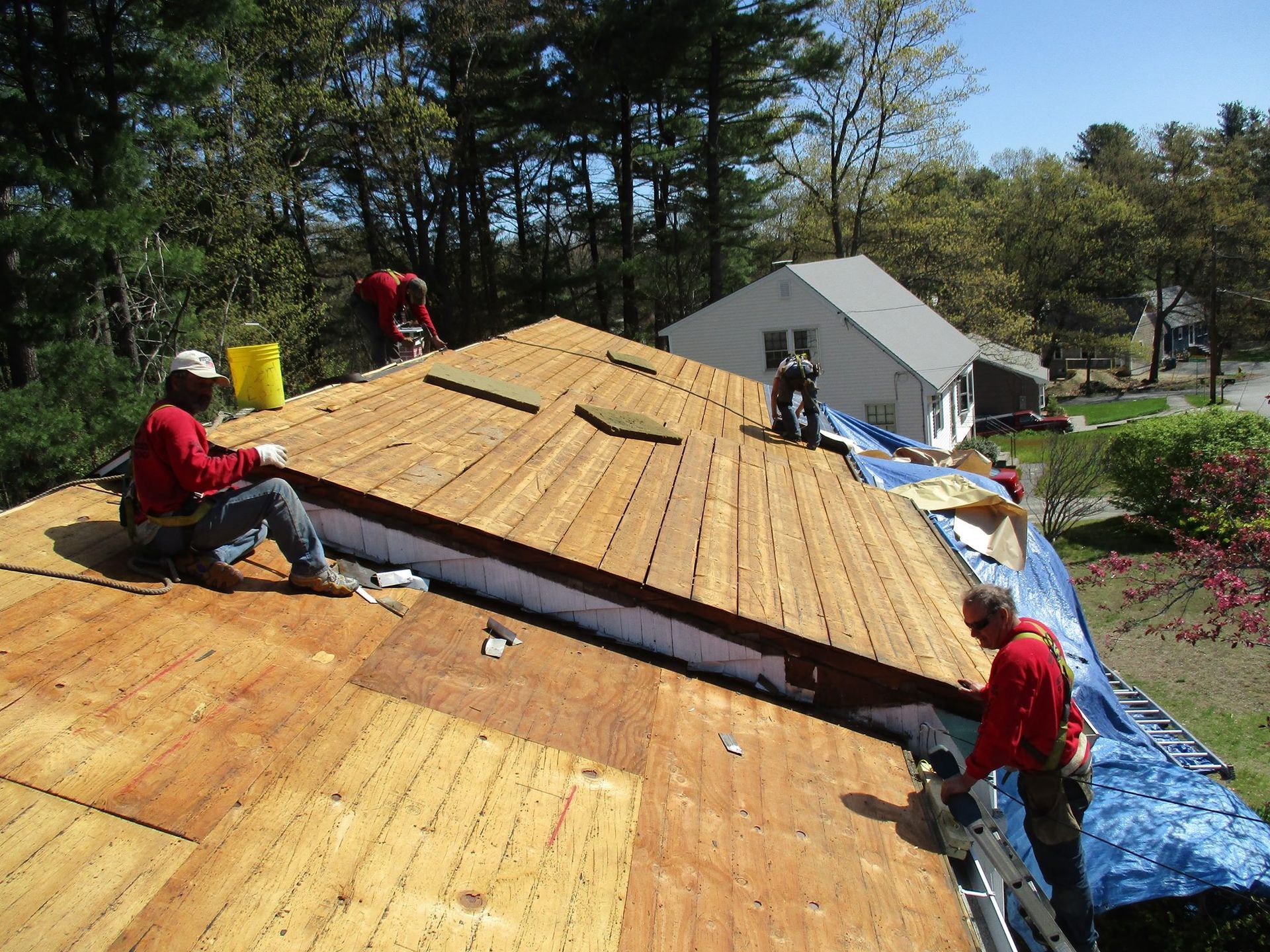 A man wearing a tool belt is working on a roof.