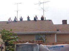 a group of people are sitting on the roof of a house .