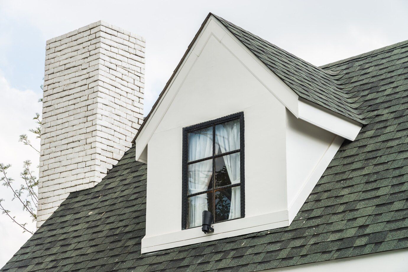 A white house with a window and chimney on the roof