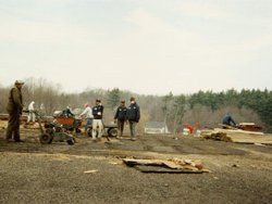 a group of people are standing on top of a dirt field .