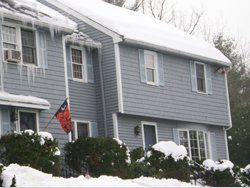 a house with snow on the ground and icicles on the roof