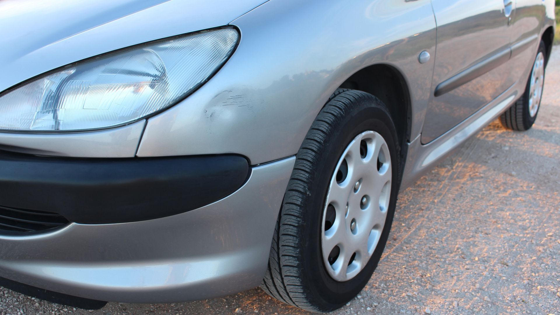 Vorderseite des silbernen Autos, Reifen, Scheinwerfer und Karosserieteil sind sichtbar.