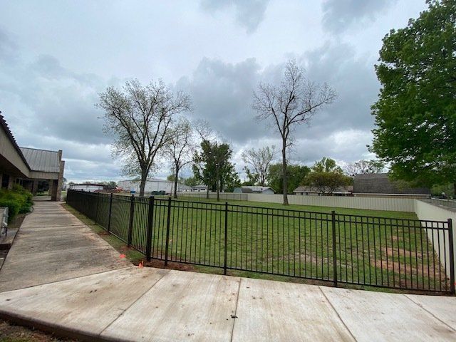 A fence surrounds a lush green field with trees in the background.