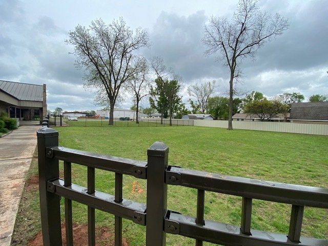 A fence surrounds a grassy field with trees in the background