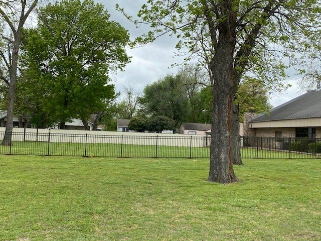 A fenced in yard with trees and a house in the background