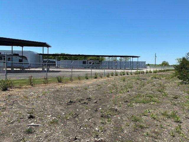 A fenced in area with a trailer parked in the background