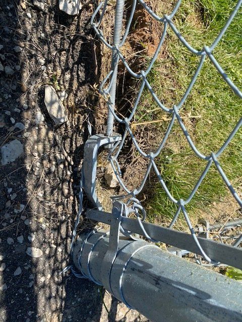 A close up of a chain link fence with a hole in it