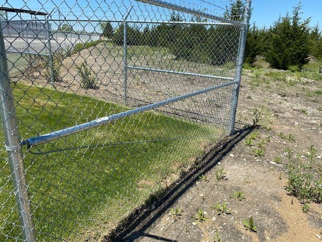 A chain link fence is sitting in the middle of a grassy field.