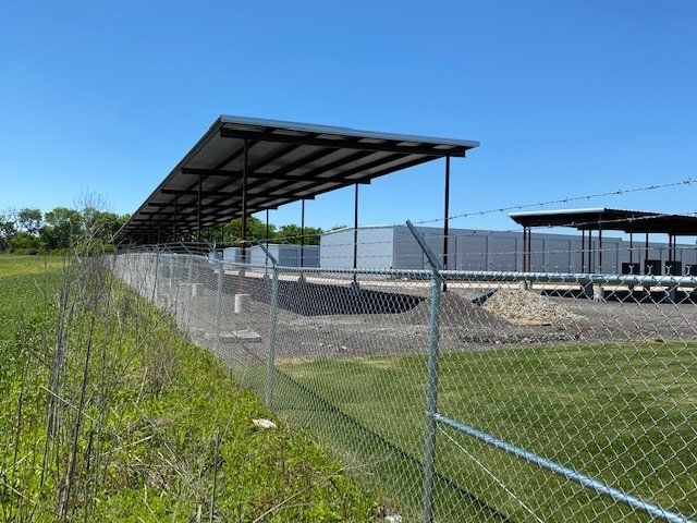 A chain link fence surrounds a building with a roof