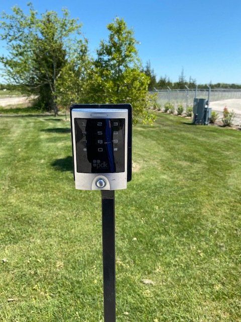 A remote control is sitting on a pole in the grass.