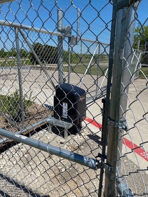 A chain link fence with a black box in the middle