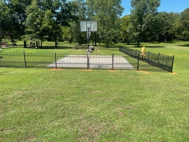 A basketball hoop is surrounded by a fence in a park.