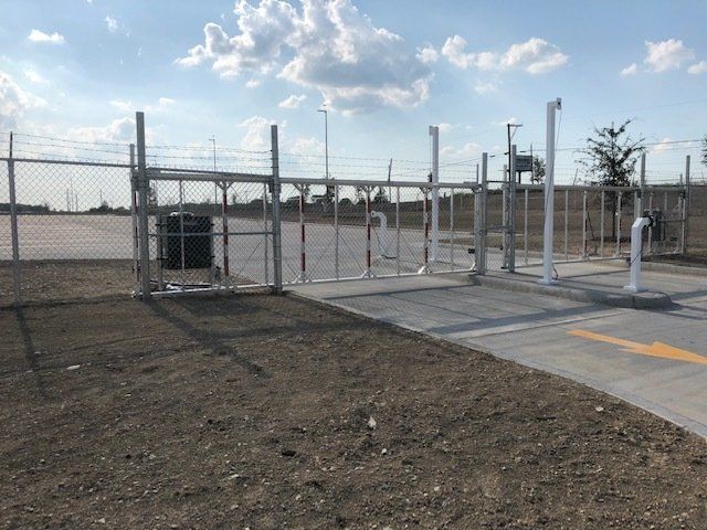 A fence with a gate in the middle of a dirt field