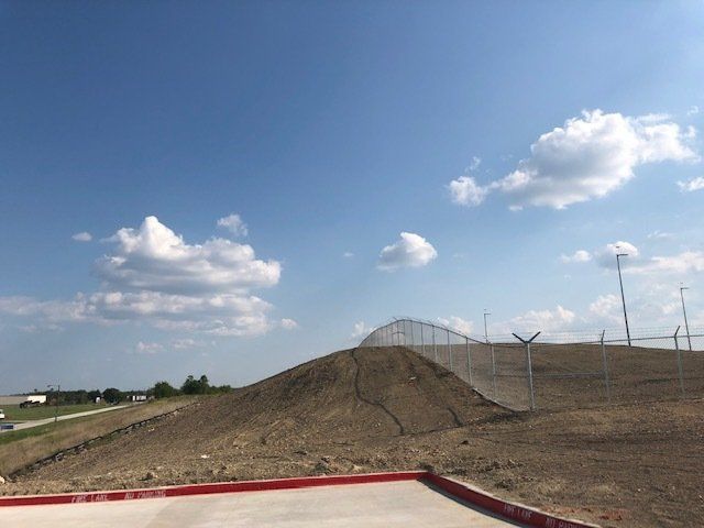 A dirt hill with a fence and a blue sky in the background