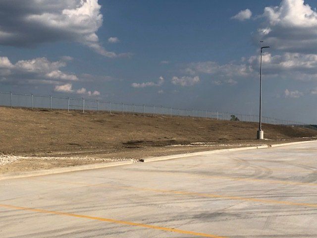 A parking lot with a fence and a blue sky in the background.