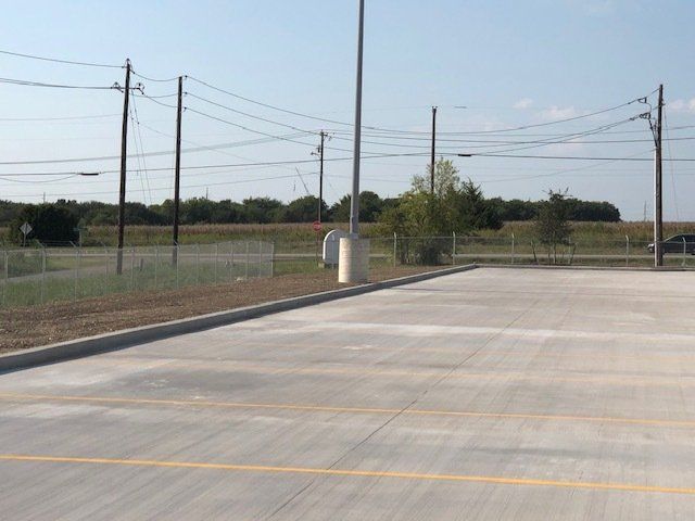 A parking lot with a fence and power lines in the background