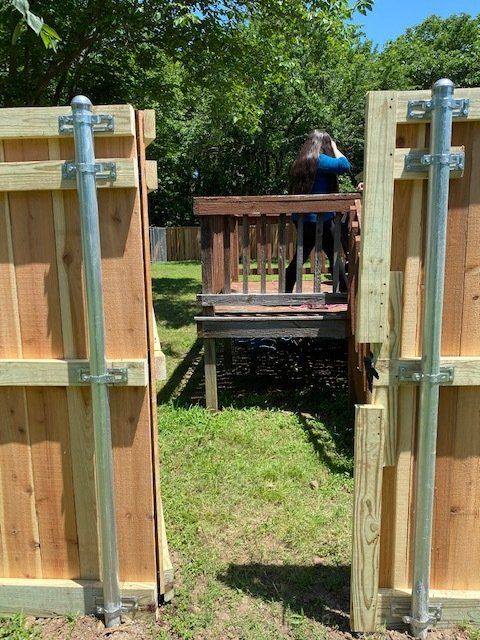 A person is standing on a deck behind a wooden fence.