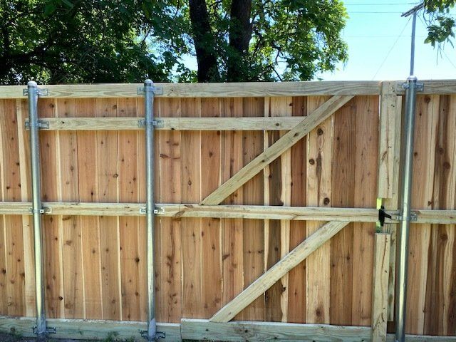 A wooden fence is being built with trees in the background.