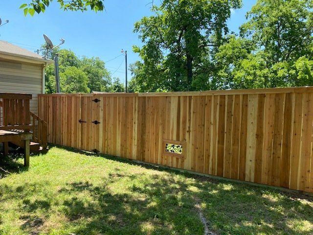 A wooden fence with a gate in the backyard of a house.