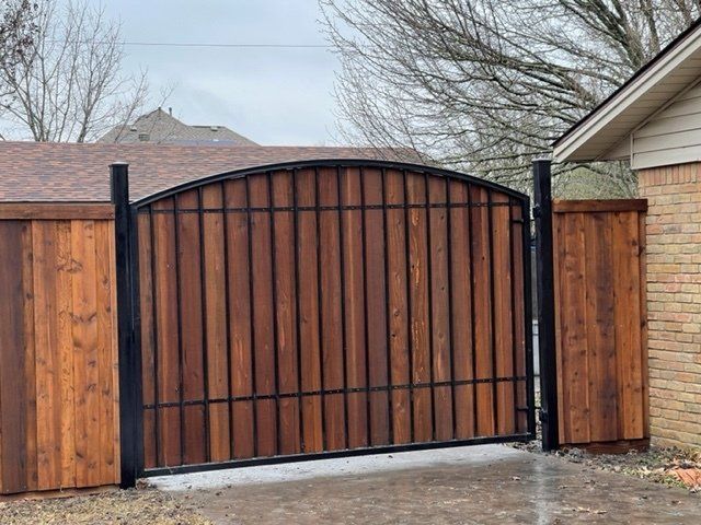 A wooden gate with a metal frame is sitting next to a wooden fence.