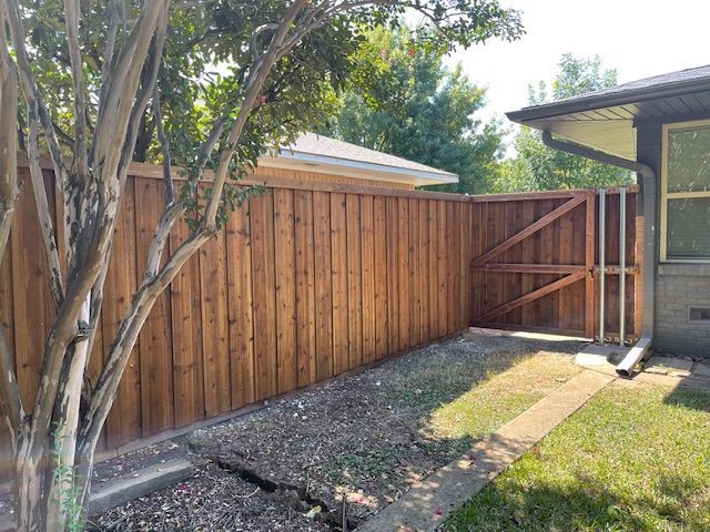 A wooden fence with a gate in the backyard of a house.