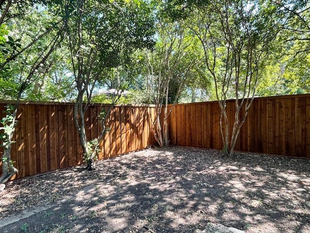 A wooden fence is surrounded by trees in a backyard.