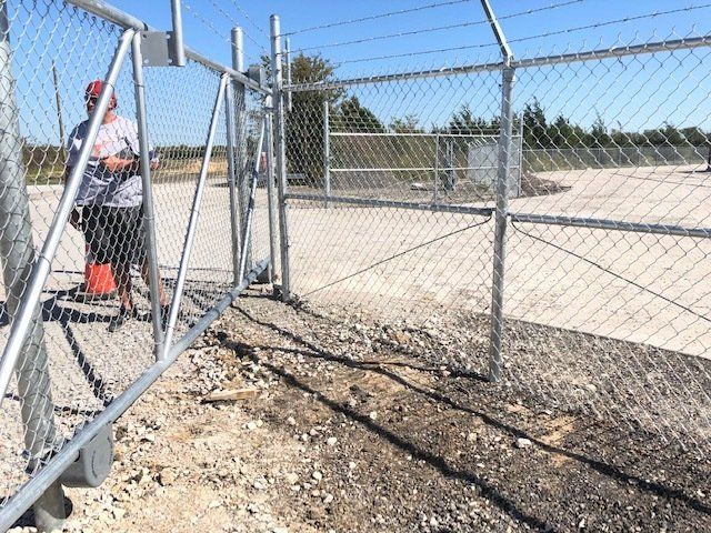 A man is working on a chain link fence.