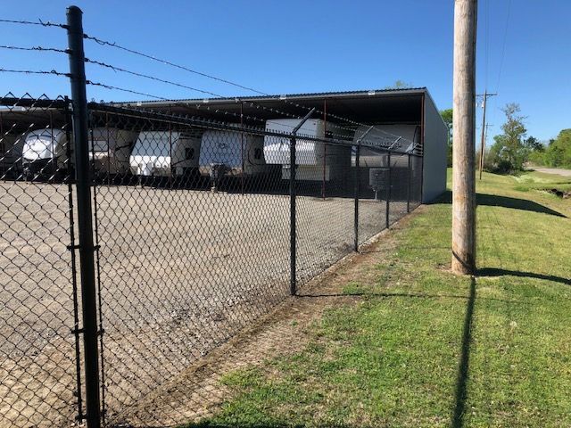 A chain link fence with barbed wire surrounding a warehouse