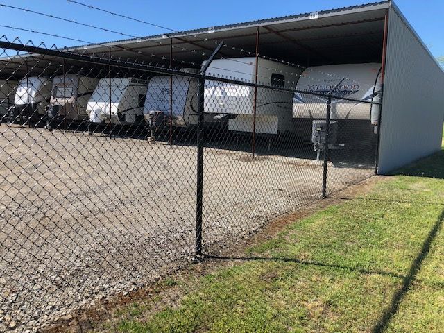 A chain link fence surrounds a row of trailers.
