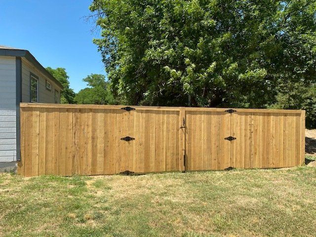 A wooden fence with a gate in front of a house.