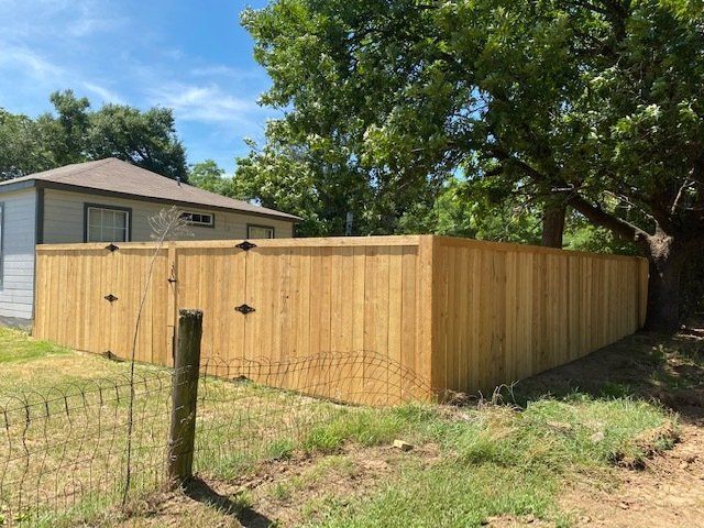 A wooden fence with a fence post in front of a house.