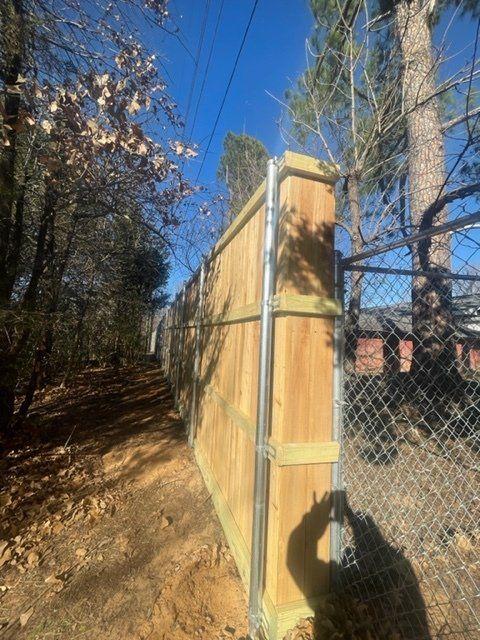 A wooden fence with a chain link fence behind it