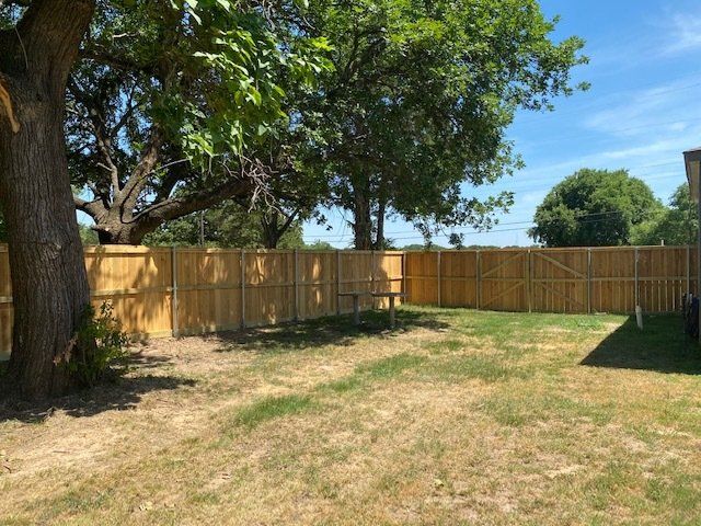 A backyard with a wooden fence and trees