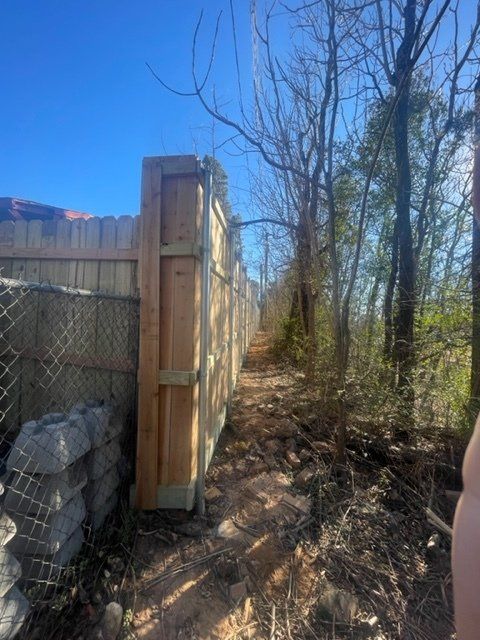 A wooden fence surrounds a dirt path in the woods