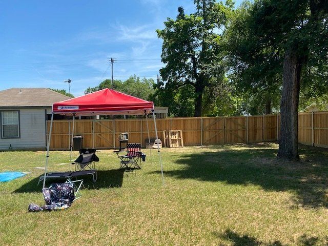 A backyard with a red canopy and chairs