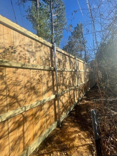 A wooden fence surrounds a dirt path in the woods