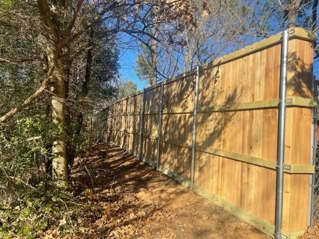 A wooden fence surrounds a path in the woods.