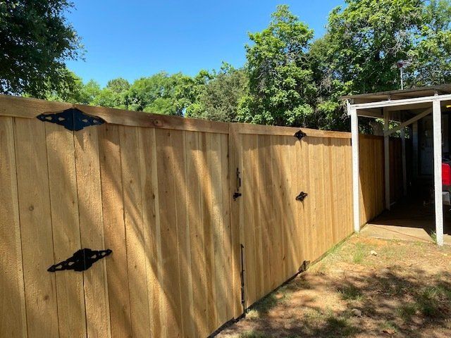 A wooden fence with a gate in the backyard of a house.