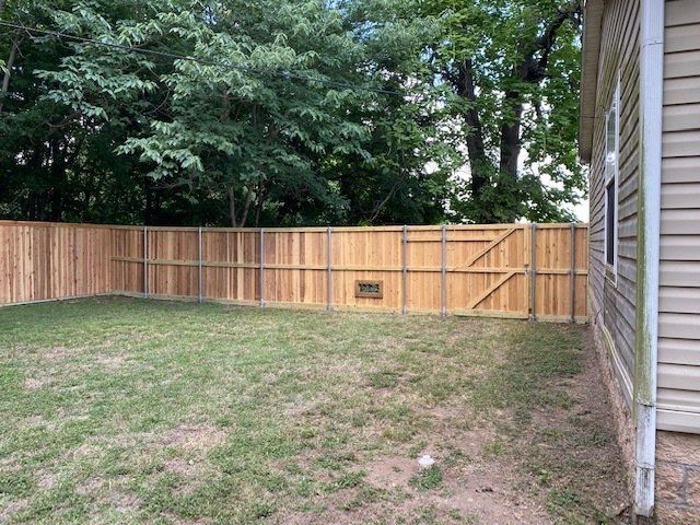 There is a wooden fence in the backyard of a house.
