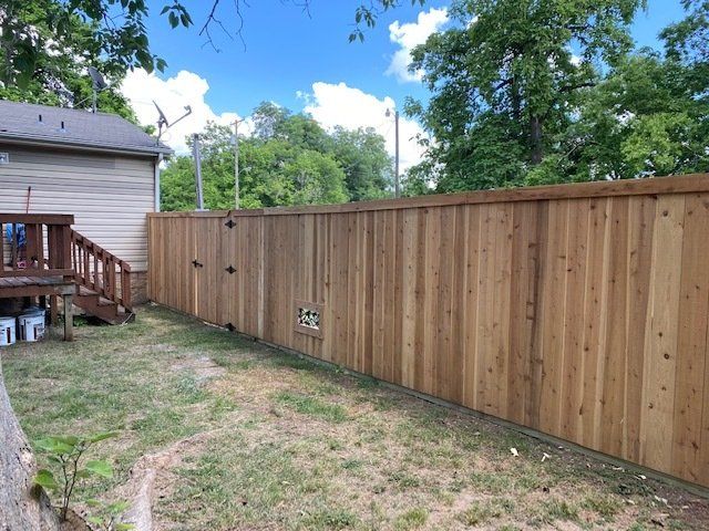 A wooden fence is in the backyard of a house.