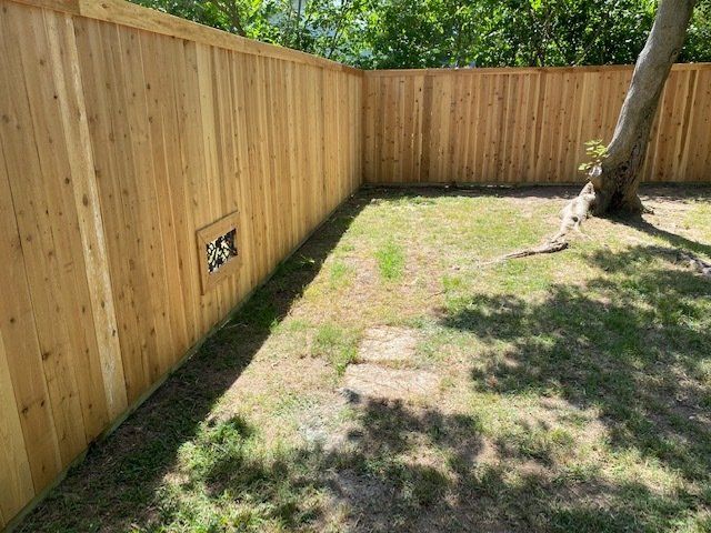 A wooden fence surrounds a lush green yard.