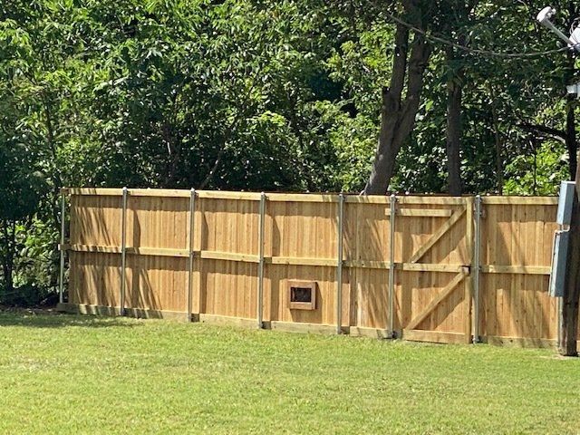 A wooden fence is sitting on top of a lush green field.