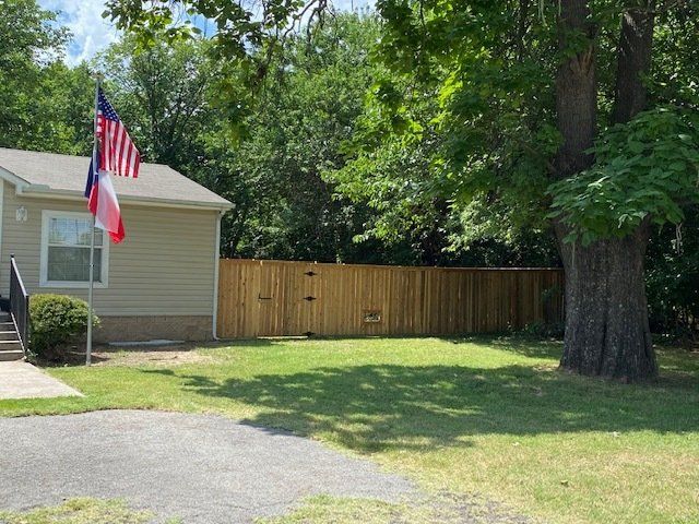 A small house with a wooden fence and an american flag in front of it.