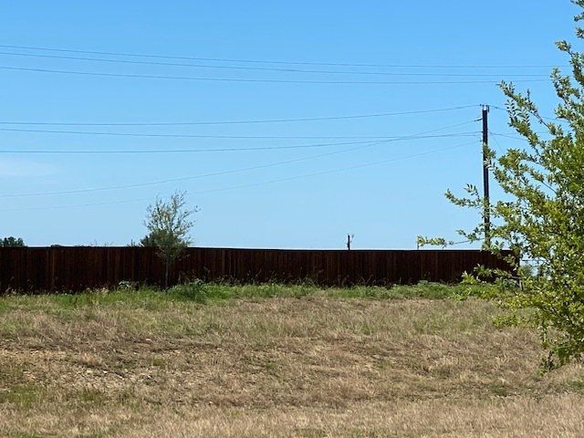 A field with a wooden fence and power lines in the background.