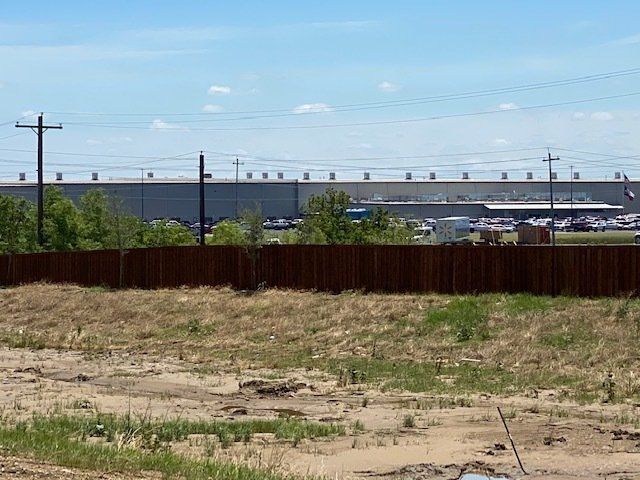 A large building is behind a wooden fence in a field.