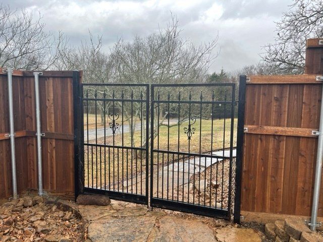A wooden fence with a metal gate leading to a field.